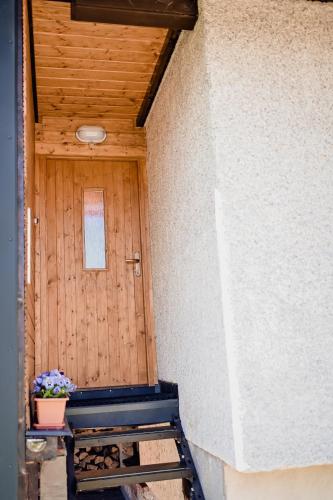 a porch with a wooden door with a potted plant at Apartmán Pod Žalým in Benecko