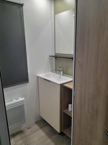 une salle de bain blanche avec un lavabo et un miroir dans l'établissement MOBIL HOME l'ALOUETTE, à Sérignan