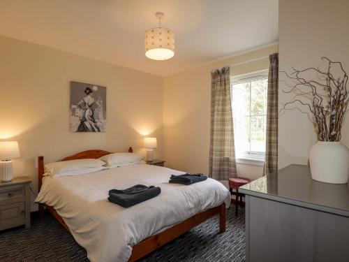 a bedroom with a bed with two black towels on it at Stone Water Cottage in Contin