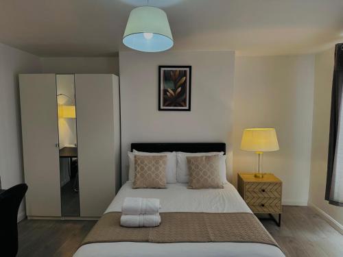 Un dormitorio con una gran cama blanca con una lámpara. en Westferry, en Londres