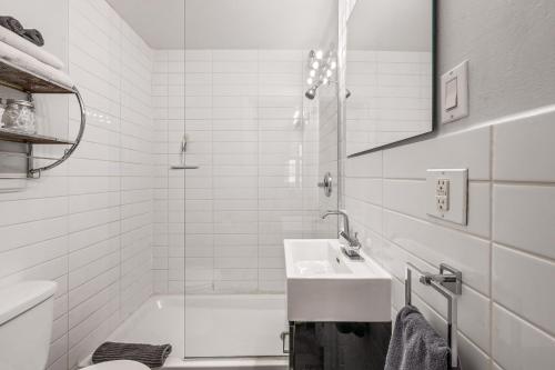 a white bathroom with a sink and a bath tub at LOFT LE RÉTRO du Centre-Ville in Quebec City