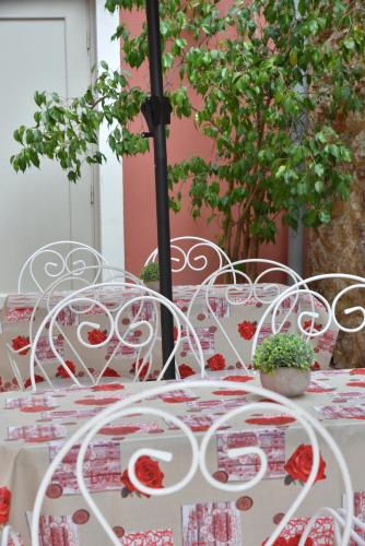 a table with white chairs with red flowers on it at Pension 2Be in Nafplio