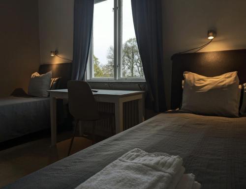 a bedroom with a bed and a desk and a window at Brunsbo G:a Biskopsgård Hotell & Konferens in Skara