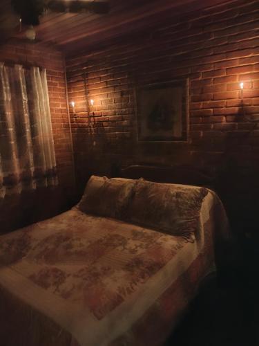 a bed in a room with a brick wall at Pousada Romântica Serra da Mata in Penedo