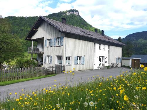 a white house with a field of yellow flowers at Haus Hirschlitten in Mellau