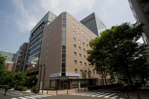 Un edificio alto en una calle de la ciudad con edificios. en Daiwa Roynet Hotel Shin-Yokohama, en Yokohama