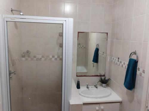 a bathroom with a sink and a shower with a mirror at Aletheia Abode in Port Alfred