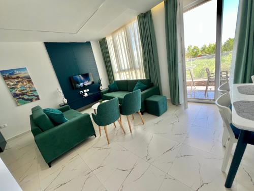 a living room with two green chairs and a television at EKAM Sun Apartments in Golem