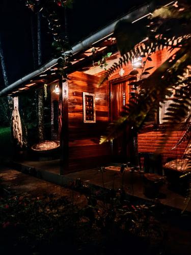a wooden cabin with two chairs in front of it at night at Pousada Romântica Serra da Mata in Penedo