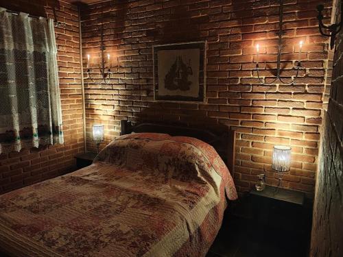 a brick walled bedroom with a bed and two lights at Pousada Romântica Serra da Mata in Penedo