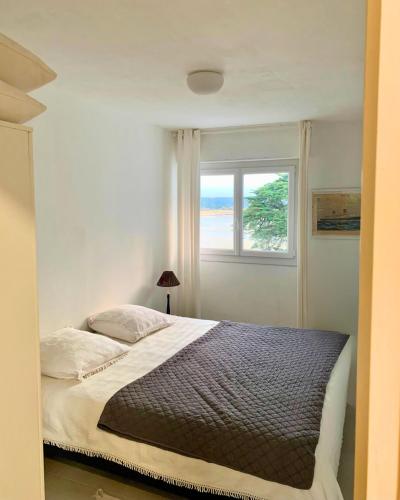 une chambre avec un grand lit avec une fenêtre dans l'établissement Carnac appartement cosy avec vue mer, à Carnac