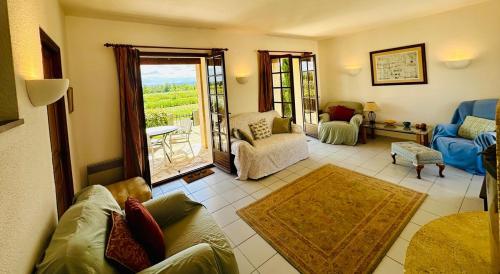 un salon avec un canapé, des chaises et une fenêtre dans l'établissement La maison du canal, à Ventenac en Minervois