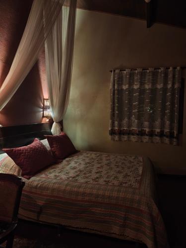 a bedroom with a bed with a curtain and a window at Pousada Romântica Serra da Mata in Penedo