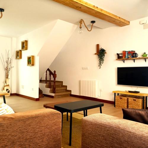 a living room with a couch and a tv and stairs at Casa frente al mar en Boiro in Magdalena