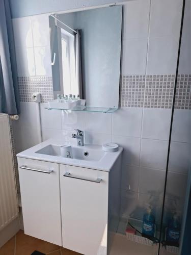 une salle de bain blanche avec un lavabo et un miroir dans l'établissement Chez Bernard et Myriam, à Wallers