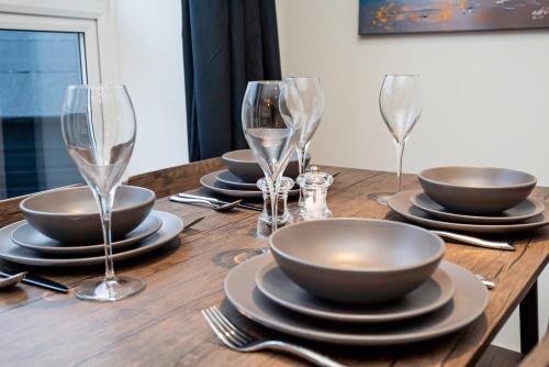 a wooden table with plates and wine glasses on it at Spacious 2 Bedroom Apartment in Central Tonbridge in Kent