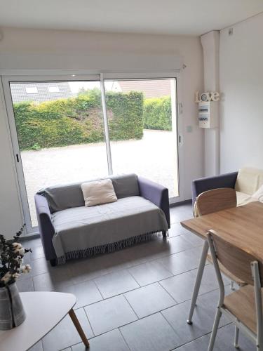 un salon avec un canapé et une grande fenêtre dans l'établissement L'Echappée Verte - Guînes, maison 2 chambres à 25min du Site des 2 Caps, à Guînes