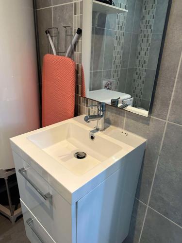 une salle de bain avec un lavabo blanc et un miroir dans l'établissement L'Echappée Verte - Guînes, maison 2 chambres à 25min du Site des 2 Caps, à Guînes