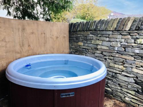 a hot tub in a yard next to a stone wall at Bridge Cottages, Bridge House & Bridge Suite, Sleeps 12 in Coniston