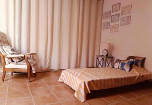 a bedroom with a bed and a chair and a window at Les Tourterelles in Cadolive