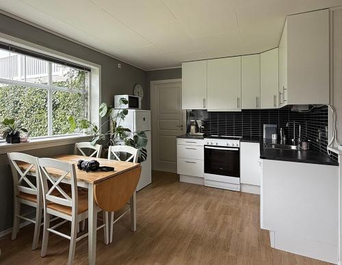 a kitchen with white cabinets and a table and chairs at Haugane in Selje