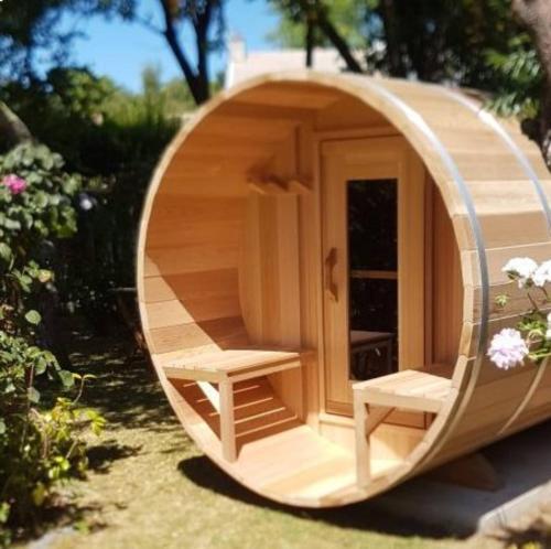 a circular wooden house with two benches in it at Domaine Le Jardin de Séraphine in Malleville-les-Grès