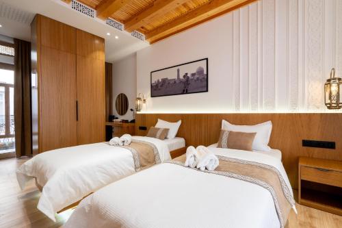 two beds in a hotel room with white sheets at Sarhad Hotel in Bukhara