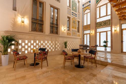 a restaurant with tables and chairs in a room with windows at Sarhad Hotel in Bukhara
