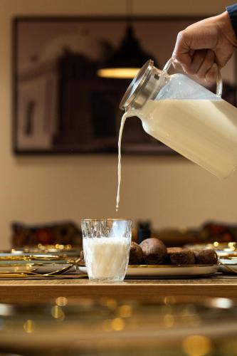 a person pouring milk from a jug into a glass at Sarhad Hotel in Bukhara