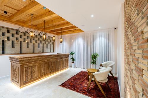 a lobby with a reception desk and chairs and a brick wall at Sarhad Hotel in Bukhara