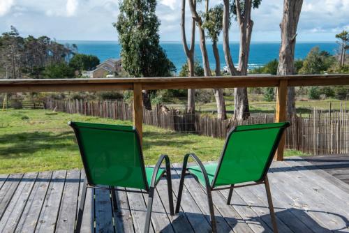 two green chairs on a deck with the ocean in the background at Quaint Cottage for 2 With Ocean Views in Gualala