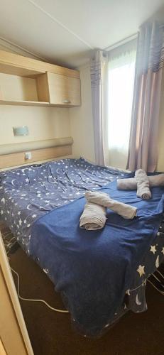 a bedroom with a blue bed with towels on it at Gull Court 3 Double Bed Caravan in Tremadoc