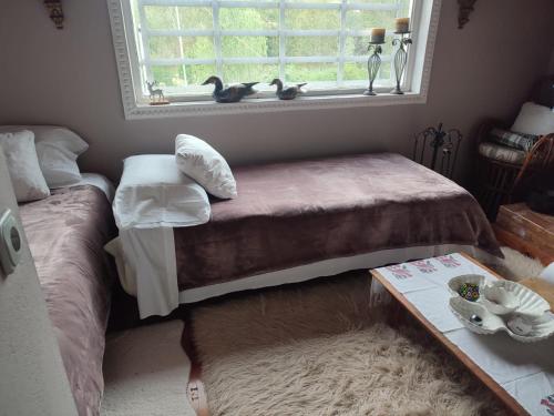 a bedroom with two beds and a window and a table at Bujtina Meraja in Koshnicë