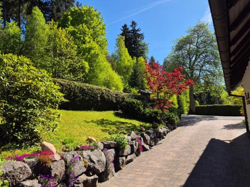 a garden with flowers and a stone wall at Ferienwohnungen Tannenhof in Willingen