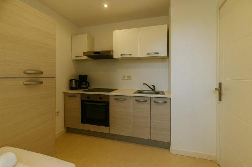 une petite cuisine avec des armoires blanches et un évier dans l'établissement Le Roule Cozy studio with charm and calm, à La Mulatière