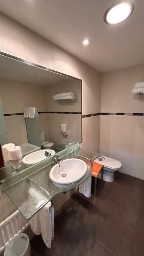 a bathroom with two sinks and a large mirror at Hotel Unzaga Plaza in Éibar