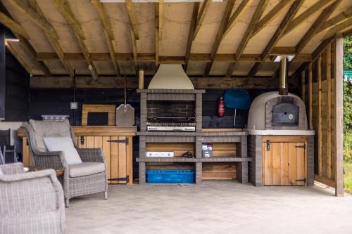 ウィンボーン・ミンスターにあるSecluded Countryside Home, Hot Tub, Onsite Pub, Pool Table, Sleeps upto 13, Perfect for a family get togetherのソファと椅子のある屋外キッチン