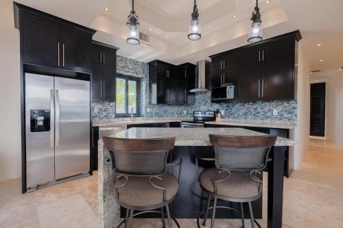 a kitchen with black cabinets and a large island with bar stools at Diamante Beachfront Suites in San Pedro