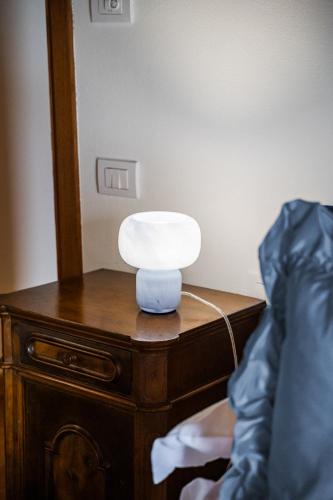 a white lamp on a wooden dresser next to a bed at Residenza Storica sulle Colline di Maranello in Fogliano