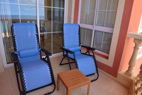 two blue chairs and a wooden stool on a balcony at Relax, descanso y una experiencia inolvidable in Costa Calma