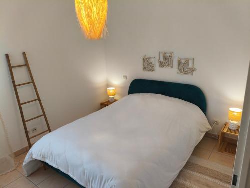 a bedroom with a white bed with a green headboard at Cocon douillet près de l'étang in Mèze