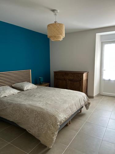 une chambre avec un lit et un mur bleu dans l'établissement Maison de campagne rénovée, à Montaron