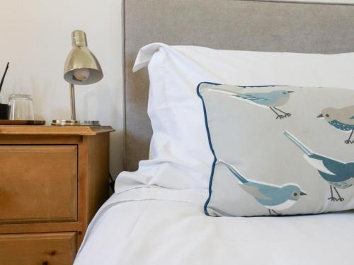 a bed with a pillow with birds painted on it at BB House in Bedford