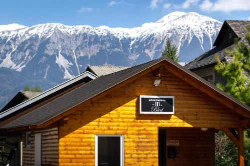 a log cabin with snow covered mountains in the background at Deluxe apartments Bled in Bled