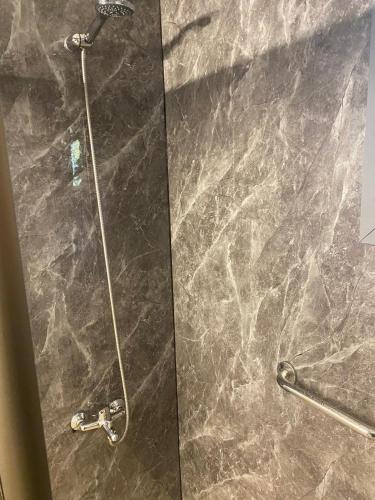 a shower stall with a glass door with a shower head at Raki Bed and Breakfast Hostel in Trape
