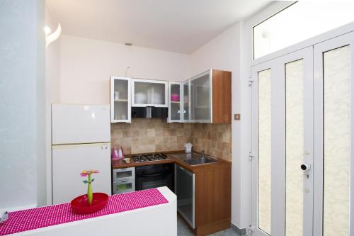 a kitchen with white cabinets and a red table at Valle dell'Eden Appartamenti in Grottammare