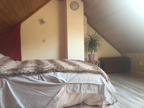 Ce lit se trouve dans un dortoir doté d'une horloge murale. dans l'établissement Appartement au calme, à La Bresse