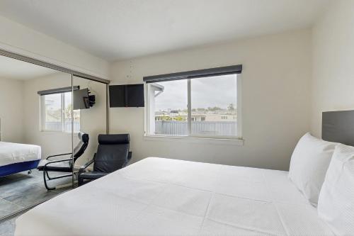a bedroom with a large white bed and a chair at Upper Level Beach Retreat in Newport Beach
