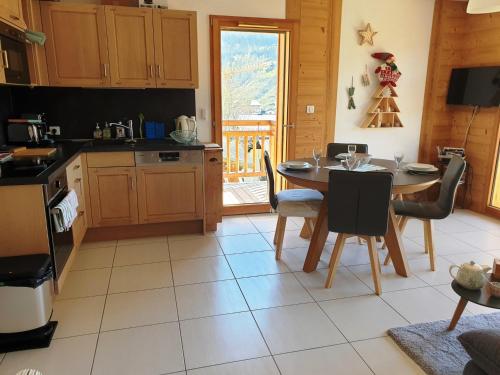 - une cuisine avec une table, une table et des chaises dans l'établissement Appartement Cosy 3 pièces avec Balcon, Garage et Wi-Fi - FR-1-598-40, aux Gets