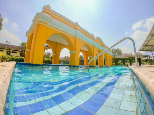 a swimming pool with a yellow and blue building at Elite Maya Hotel & Spa in Antigua Guatemala
